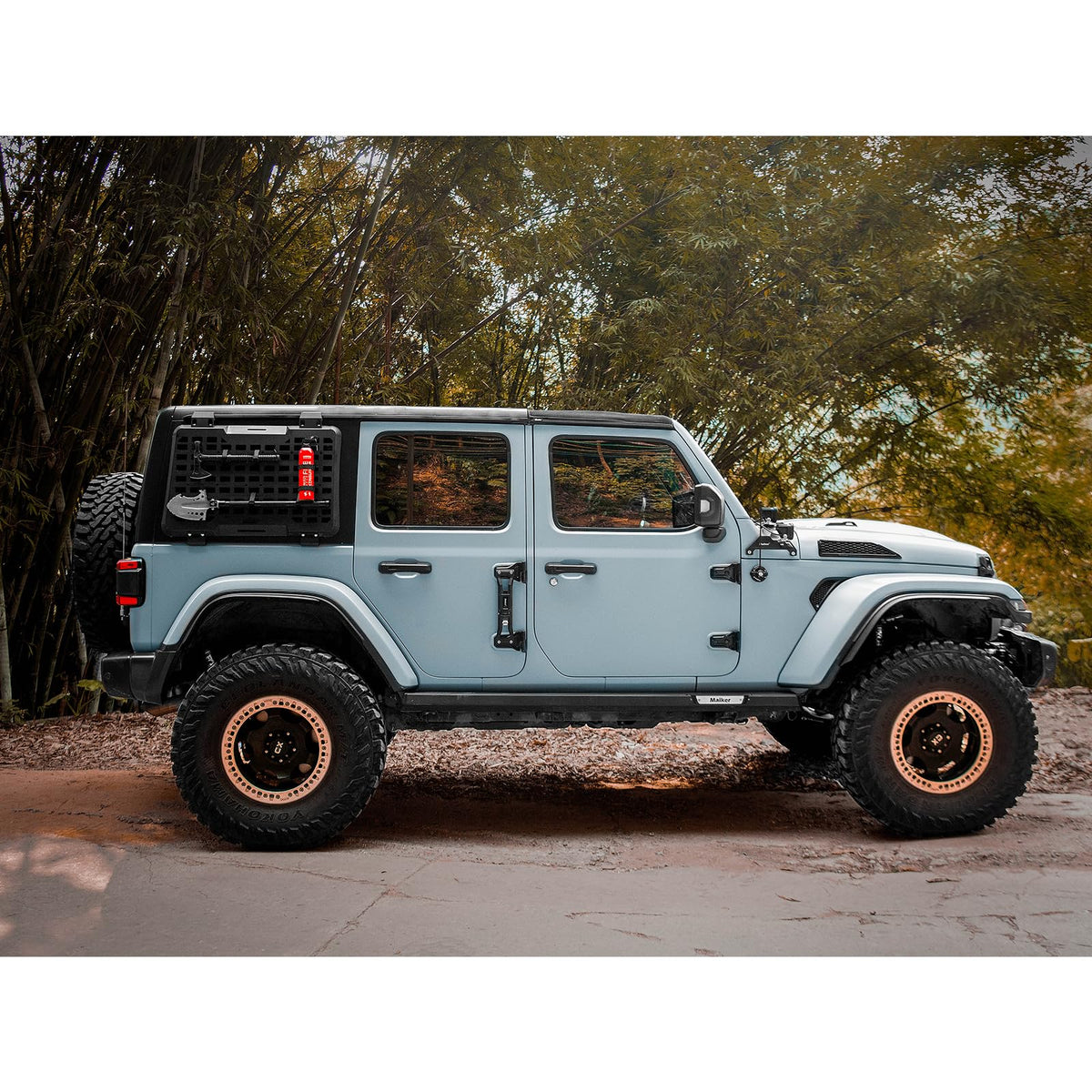 Side view of a Jeep with an exterior rear-window MOLLE panel carrying tools and a fire extinguisher